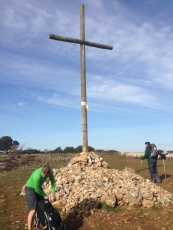 Caroline placing a rock in front of the cross as a prayer. Pilgrims bring rocks from their homelands as prayers to this cross.
